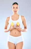 As sour as your ex. Portrait of a young woman holding lemons in her hands while posing against a grey background.