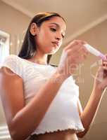 Im just waiting for the line to appear. a young woman taking a pregnancy test at home.