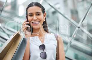 Portrait of a woman smiling while staying connected with a cellphone while out shopping. Trendy female on a call telling friends about a sale or discount at a mall. Enjoying the weekend with retail therapy.