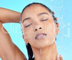 Addicted to the glow. Shot of an attractive young woman showering against a blue background.