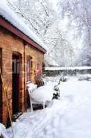 Quiet old house in snow landscape and frozen garden. A red brick cottage in Europe with thick white frost covered yard in winter with copy space. Magical wonderland of snowfall in Scandinavia