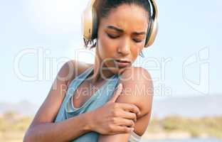 Young african american sportswoman suffering from shoulder pain while training. Woman holding her shoulder in pain while exercising outside. Overworking can lead to injury