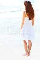 Young female standing on the sea shore. Rear view of a young female standing on the sea shore.