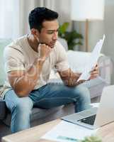 I need to diversify my stock portfolio. a handsome young man sitting alone in his living room and looking contemplative while calculating his finances.