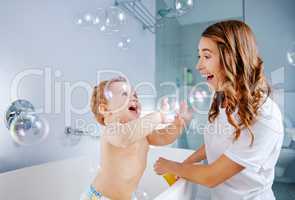 Bubbles make bath time more fun. Shot of a mother bathing her baby at home.