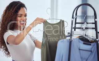 One beautiful hispanic woman checking out clothing while shopping in a retail store. Attractive mixed race female looking for sales while doing some retail therapy. Spending and consumerism