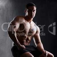 All that muscle doesnt come from sitting on the couch. an athletic young man posing shirtless against a dark background.