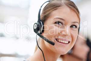 Service with a smile. Closeup of a pretty receptionist with a headset on and looking away.