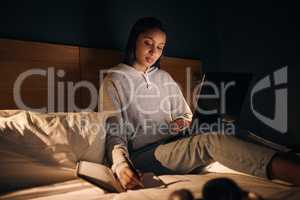 Some final exam prep. Cropped shot of an attractive young woman studying late at night in her bedroom at home.