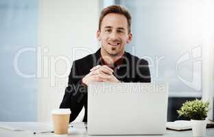 Each day brings tons of new opportunities for success. Portrait of a young businessman working on a laptop in an office.