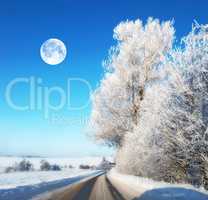 The moon in winter landscape. Road with ice on a winter landscape during noon. The Moon shines through clear clouds