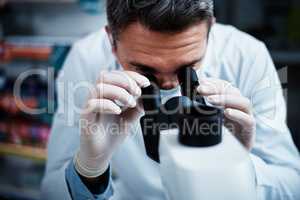 Always on the lookout to better treat illness. a mature man using a microscope while conducting pharmaceutical research.
