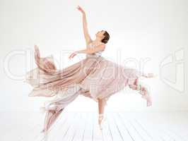 Shes got a rehearsal coming up. Full length shot of an attractive young female ballerina practicing in her dance studio.