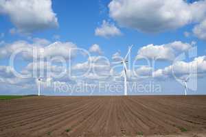 Wind turbines and environmental infrastructure isolated against blue sky with copy space on an empty energy farm. Propellers converting sustainable energy into electric power in remote and rural area