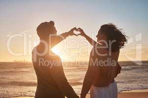 Biracial couple holding their hands together in a heart shape at the beach. Biracial couple holding their hands together in a heart shape at the beach.