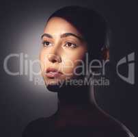 A major component of healthy skin is a natural glow. Studio shot of a beautiful young woman posing with light beam against her face.