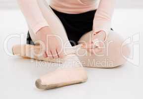 A loose shoe makes for a messy performance. an unrecognizable ballet dancer fitting her shoes on before practice.