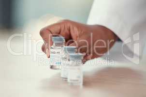 Closeup of doctor putting bottles of covid vaccine on a table. Hands of a doctor holding corona virus antidote. Healthcare professional putting medicine on a table. Hands of a gp holding covid cure