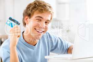 Lets do some retail damage. Shot of a young man using his laptop to make online payments.