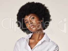 Studio portrait of a young stunning African American woman with a beautiful afro. Confident black female model showing her smooth complexion and natural beauty while posing against a grey background