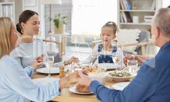 A tradition as old as time. a beautiful family blessing the food with a prayer at the table together at home.