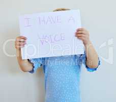 Little girl protesting against domestic violence and child rape with a sign. Unknown caucasian child standing alone and holding a protest poster against white background. Kid campaigning against abuse