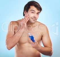 They find me irresistible. Shot of a young man applying cologne to his skin against a studio background.