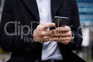 Contacting the office. Croppeds shot of an unrecognizable businessman checking his messages during his morning commute into work.