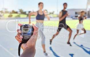A sport coach timing athletes progress using a stopwatch. .Blurred athletes racing towards finish line and breaking the record. Stopwatch measuring time for a marathon at a sports event.