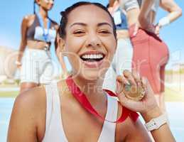 Closeup portrait of mixed race athletic woman showing gold medal from competing in sports event. Smiling fit active latino athlete feeling proud after winning running race.