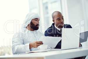 Teaming up to work on a business task. two businessmen using a digital tablet and laptop while having a discussion in a modern office.