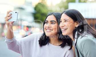 Less competing, more connecting. Shot of two young businesswomen taking selfies with a smartphone against an urban background.