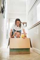 Happy mother pushing son in cardboard box enjoying their new home.Little boy having fun riding in carton box. Encouraging pretend play