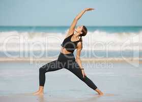 Stretch and strengthen your way to a better body. a young woman doing a crescent lunge while practising yoga at the beach.