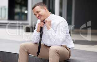 A young mixed race business man taking off his tie while sitting outside. Feeling negative about job loss or a failed interview. Unemployment has got him feeling down and depressed. Ready to quit
