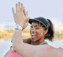 Two friends sharing high five and celebrating their success while being active outdoors. Cheerful woman out kayaking and motivating her partner while enjoying a water activity on a lake in summer