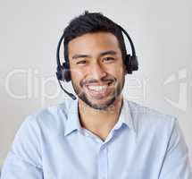 Portrait of a young mixed race call center agent working in his office. Operator at his reception job. Hispanic man wearing a wireless headset smiling while directing calls in customer service