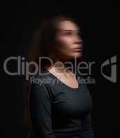 Who am I. Studio shot of a woman standing against a black background with a blurred face.