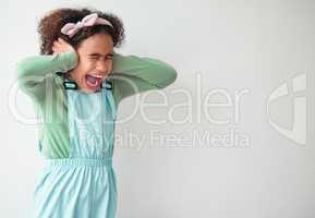 Little girls are precious gifts. Shot of a young girl covering her ears against a grey background.