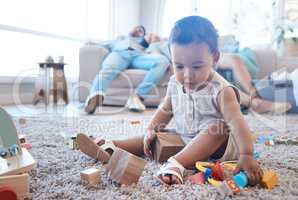 When exhaustion wins. Shot of a little girl playing on the floor while her parents nap in the background.