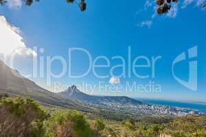 Landscape of a mountain and city in South Africa. Wide angle of shrubs and wild bushes against a bright blue horizon of Cape Town. View of Lions Head, a popular travel destination near Table Mountain