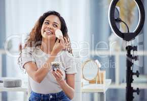 One hispanic woman recording a makeup tutorial for her beauty blog with her phone while sitting at home. African american female influencer live streaming her cosmetic review and recommendation online