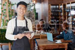 Portrait of smiling asian small business owner in his restaurant holding a wireless digital tablet. Young businessman using a digital tablet to do stocktake and order products online through shopping