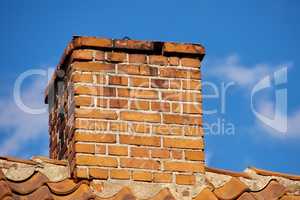 Copy space with a chimney on the rooftop of a house or building against a blue sky background. Brick construction of an exterior escape chute for ventilation of air and smoke from a fireplace or oven