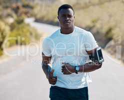 One handsome young african american athlete listening to music while out for a jog in nature. Dedicated black man working out alone outside. His fitness routine includes running to increase endurance