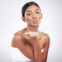 A kiss from me to you. Studio portrait of an attractive young woman blowing a kiss against a grey background.