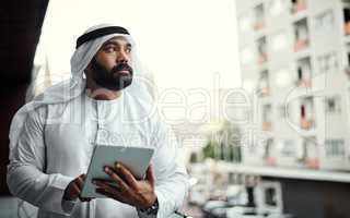 Connected to the word. a businessman dressed in traditional Islamic clothing working on his office balcony.