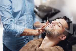 Hes ready to be pampered. a handsome young man getting groomed by a barber.
