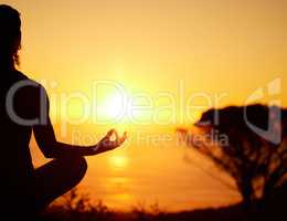 Rearview silhouette yoga woman meditating with legs crossed for outdoor practice in remote nature. Mindful person sitting alone and balancing for mental health at sunset. Serene and zen in lotus pose