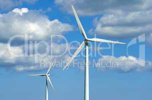 Wind turbines and environmental infrastructure isolated against blue sky with copy space on empty energy farm. Propellers converting sustainable energy into electric power in remote and rural area